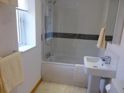 a white bathroom with a shower and a sink at THE CHAPEL 