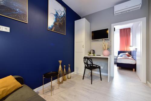 een kamer met een blauwe muur, een bureau en een bed bij Candy Apartments Warszawa in Warschau