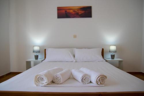 Una cama blanca con tres toallas enrolladas. en Nikolaos Residence, en Kiato