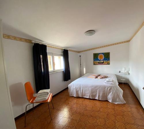 1 dormitorio con 1 cama blanca y 1 silla en La casa di Anita, en Civita Castellana