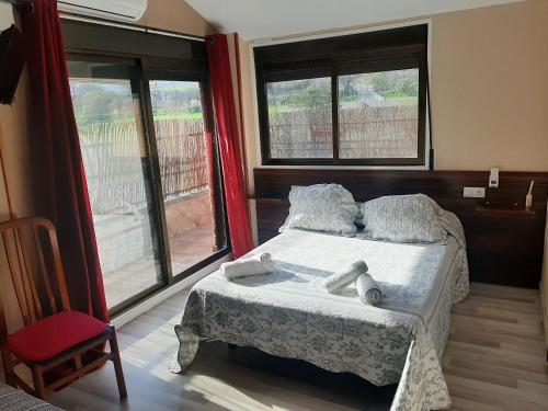 1 dormitorio con 1 cama, 1 silla roja y ventanas en Hostal Escarla, en Aren