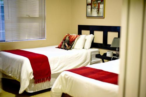 a bedroom with two beds with red blankets on them at Valleyside Executive Apartments in Ezulwini
