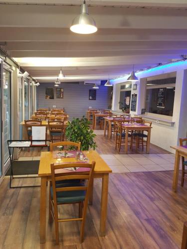 un ristorante con tavoli e sedie in legno di LE SPORTING a Beaumont-sur-Lèze