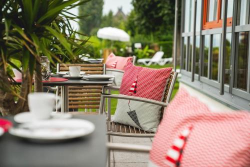 an outdoor patio with tables and chairs with red and white pillows at Strandhaus Eberle in Immenstaad am Bodensee
