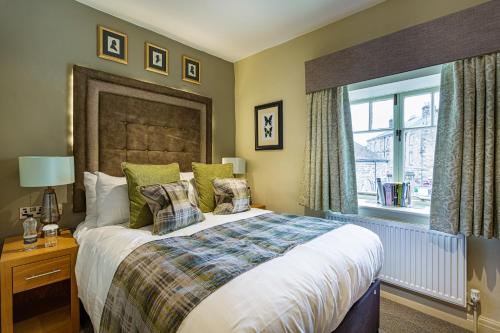 a bedroom with a large bed and a window at The Rutland Arms Hotel, Bakewell, Derbyshire - The Coaching Inn Group in Bakewell