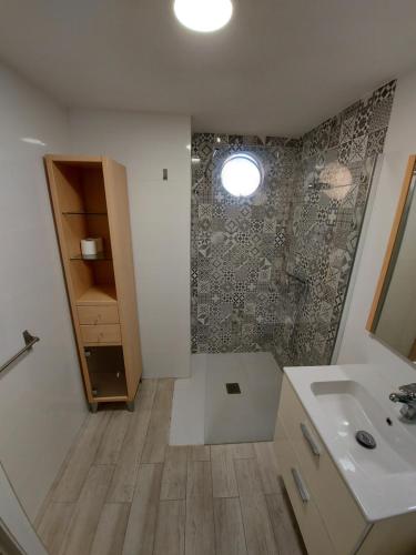 een badkamer met een douche, een wastafel en een spiegel bij APARTAMENTO ROMA XI in Playa de Gandia