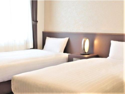 2 Betten in einem Hotelzimmer mit einer Lampe dazwischen in der Unterkunft BANDE HOTEL OSAKA - Vacation STAY 98144 in Osaka
