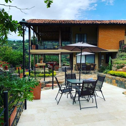 a patio with a table and chairs and an umbrella at Hotel Casas de Campo El Ciruelo in San Gil