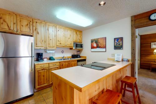 a kitchen with wooden cabinets and a stainless steel refrigerator at Anaconda 102 in Copper Mountain