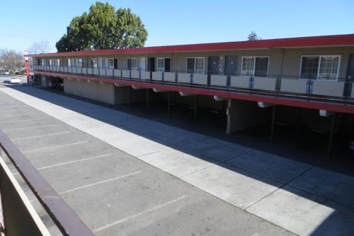an empty building with a red roof and a sidewalk at Capri Motel in Redwood City