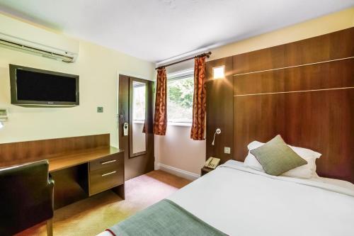a hotel room with a bed and a tv at The Bridge House Hotel in Reigate