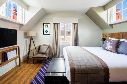 a hotel room with a bed and a tv and a chair at Hotel Indigo - Durham by IHG in Durham