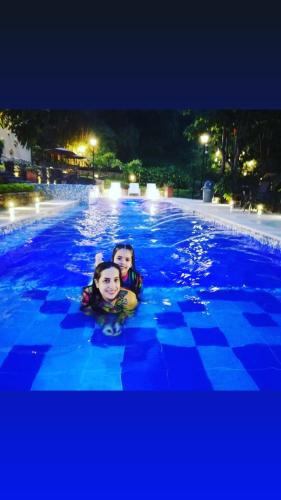two children are in a swimming pool at night at Hotel Casas de Campo El Ciruelo in San Gil