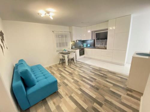 a living room with a blue couch and a kitchen at Apartament BLUE in Poznań