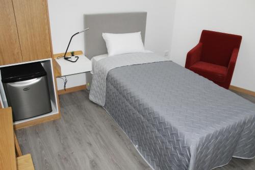 a bedroom with a bed and a chair and a tv at ALOJAMENTO GIRASSOL - Guest House - Quarto com casa de banho privativa in Castelo Branco