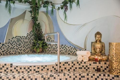 a statue of a buddha in a bath tub at Apparthotel Feldhof - Living and Bistro in Nova Ponente