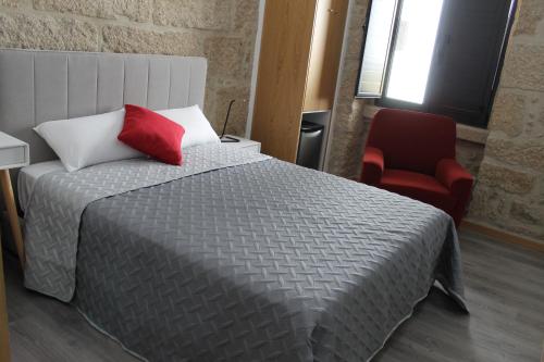 a bedroom with a bed and a red chair at ALOJAMENTO GIRASSOL - Guest House - Quarto com casa de banho privativa in Castelo Branco