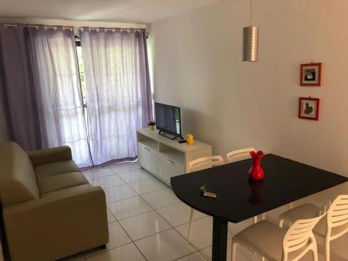 - un salon avec une table, un canapé et une télévision dans l'établissement PRAIA RESIDENCE 303A - Porto de Galinhas - PE, à Porto de Galinhas