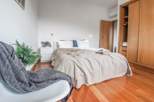 a white bedroom with a bed and a chair at Trendy Apartments in Funchal