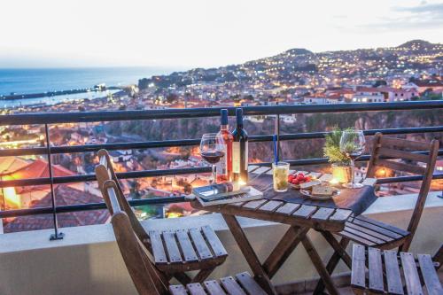 a table with two chairs and wine glasses on a balcony at Trendy Apartments in Funchal
