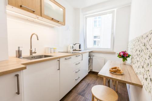 eine Küche mit weißen Schränken und einem Holztisch in der Unterkunft Vintage Tomasza 25 Apartments in Krakau