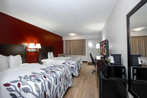 a hotel room with two beds and a flat screen tv at Red Roof Inn Bloomington - Normal/University in Bloomington