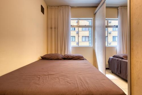 a bed in a small room with a window at Ótimo apartamento no Centro mobiliado e com garagem in Curitiba