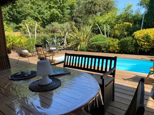 a table and chairs on a deck with a pool at Villa piscine chauffée & spa sur le Bassin d Arcachon - proche plage et océan in Lanton