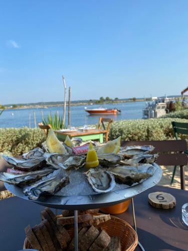 a tray of oysters on a table next to the water at Villa piscine chauffée & spa sur le Bassin d Arcachon - proche plage et océan in Lanton