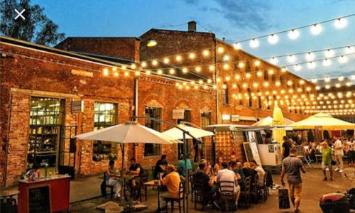 a group of people sitting at tables outside a building with lights at Hollywood Apartament Kosciuszki in Łódź
