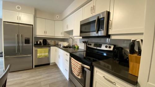 a kitchen with stainless steel appliances and white cabinets at Amber Hotel in Grand Bend