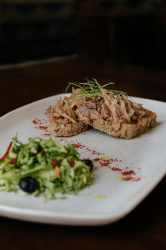 a white plate with a piece of meat and a salad at Casa das Muralhas in Covilhã