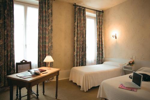 a bedroom with two beds and a desk with a laptop at Hotel Du Nord in Besançon