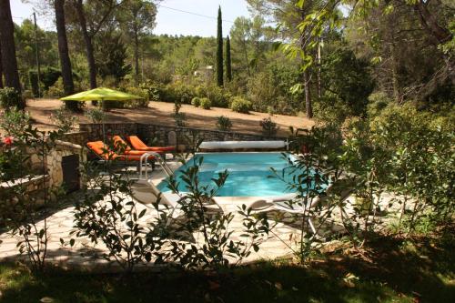 - une piscine dans une cour avec des chaises et un parasol dans l'établissement Logis au milieu des pins, à Le Puy-Sainte-Réparade