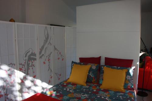 um quarto com uma cama com almofadas amarelas e vermelhas em Logis au milieu des pins em Le Puy-Sainte-Réparade