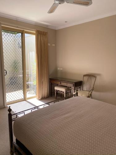 a bedroom with a bed and a desk and a window at Acacia Terraces in Echuca