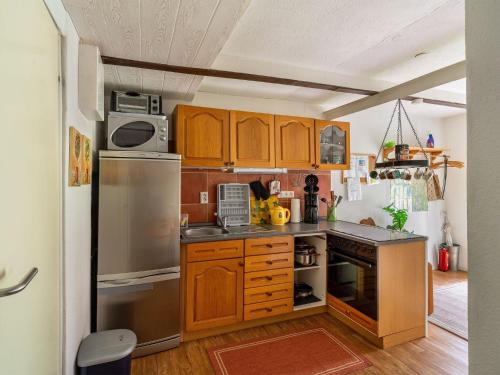 a kitchen with wooden cabinets and stainless steel appliances at Quaint Holiday Home near Forest in Stuer in Stuer