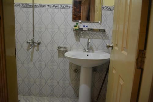 Rose Palace Hotel, Liberty في لاهور: حمام مع حوض أبيض ومرآة