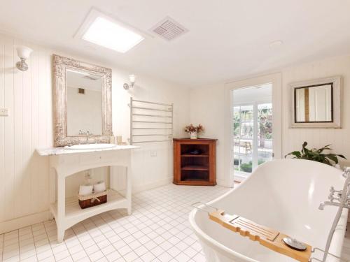 een witte badkamer met een bad en een wastafel bij Aylmerton House and Cottage for 14 Southern Highlands in Mittagong