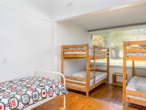 a bedroom with two bunk beds and a window at Bimbadgen at Hyams Beach in Hyams Beach