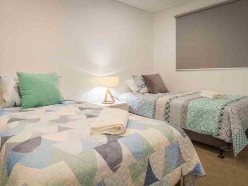 a bedroom with two beds and a lamp in it at Blue Waves Kiama in Kiama