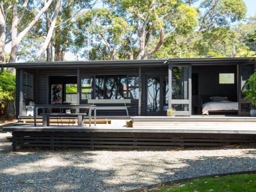 a black house with a porch and a bed at Black Shack on Hyams Beach in Hyams Beach