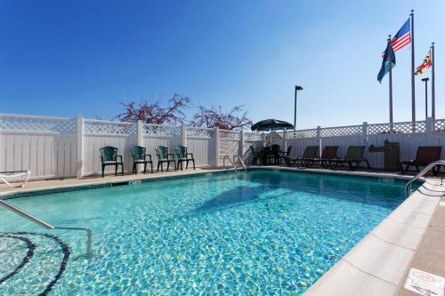 a large swimming pool with chairs and a fence at Country Inn & Suites by Radisson, Bel Air-Aberdeen, MD in Bel Air