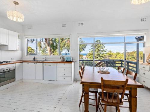 a kitchen with a table and chairs and a large window at Bombora Gerroa in Gerroa