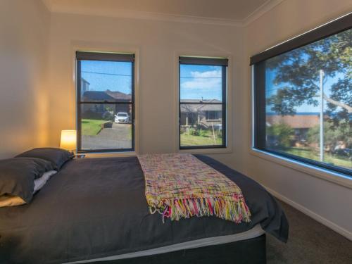 Un dormitorio con una cama y dos ventanas. en Coastline Boat Harbour Gerringong, en Gerringong