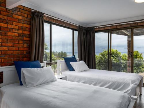 two beds in a room with a large window at Jewel of Gerroa Gerroa in Gerroa