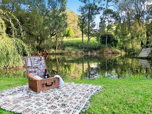 a chair sitting on a rug next to a lake at Mirrabooka Burrawang in Burrawang