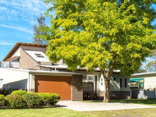 a tree in front of a house with a garage at Majestic on Palm Beach in Sanctuary Point