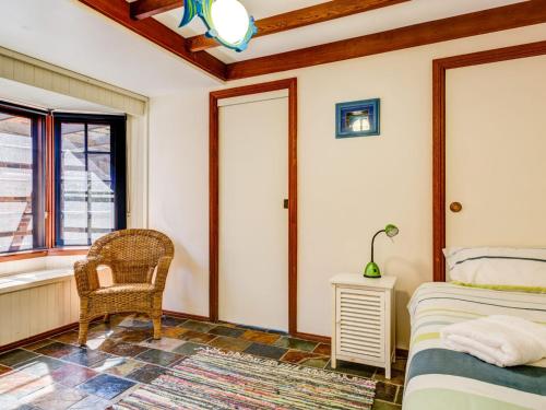 um quarto com uma cama, uma cadeira e uma janela em Mystic Sands Gerroa em Gerroa