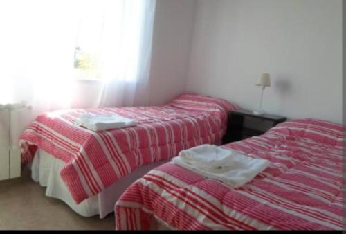 2 camas en una habitación con mantas rojas y blancas en DEPARTAMENTO CALAFATE CENTRICO en El Calafate
